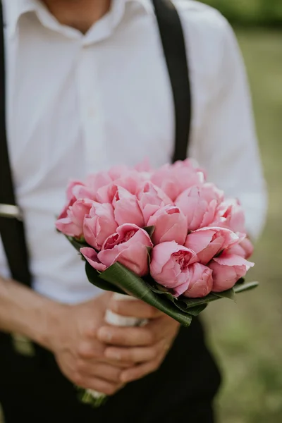 일몰에 숲에서 그의 손에 꽃의 꽃다발과 함께 포즈 웨딩 신랑의 초상화 — 스톡 사진