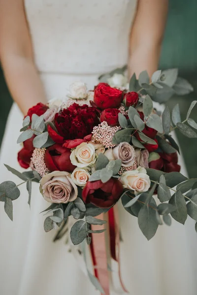 Porträt einer Hochzeitsbraut, die in einem weißen Hipster-Kleid mit Blumen in den Händen im Wald bei Sonnenuntergang posiert — Stockfoto