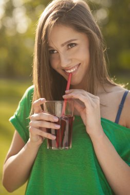 Bir bardak meyve suyu onun elinde tutan bir kızın güzel gülümseme
