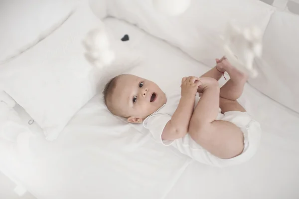Милый мальчик, играющий и смеющийся в постели — стоковое фото