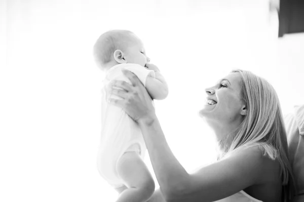 Beautiful mother portrait playing with her cute little boy on the sofa — Stock Photo, Image