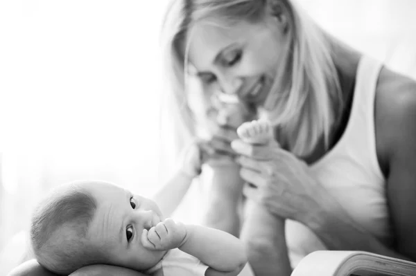 Siyah ve beyaz güzel anne portre sevimli küçük oğlu ile kanepede oynarken — Stok fotoğraf