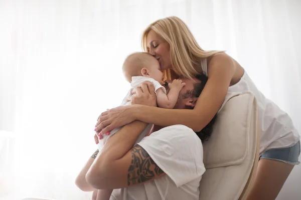 Casal sorridente brincando com seu bebê recém-nascido amado no sofá — Fotografia de Stock