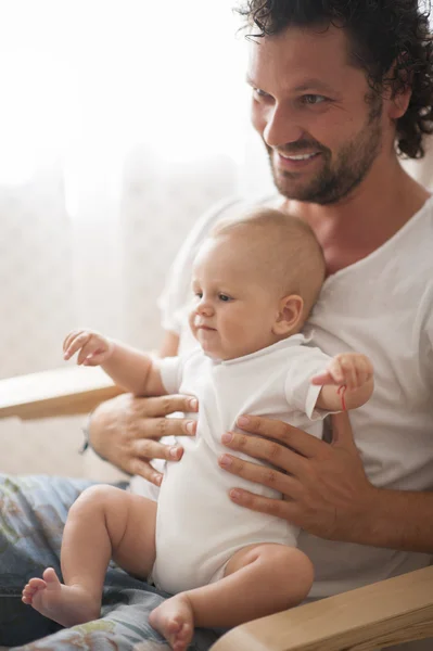 Pai brincando com bonito bebê recém-nascido menino no sofá — Fotografia de Stock