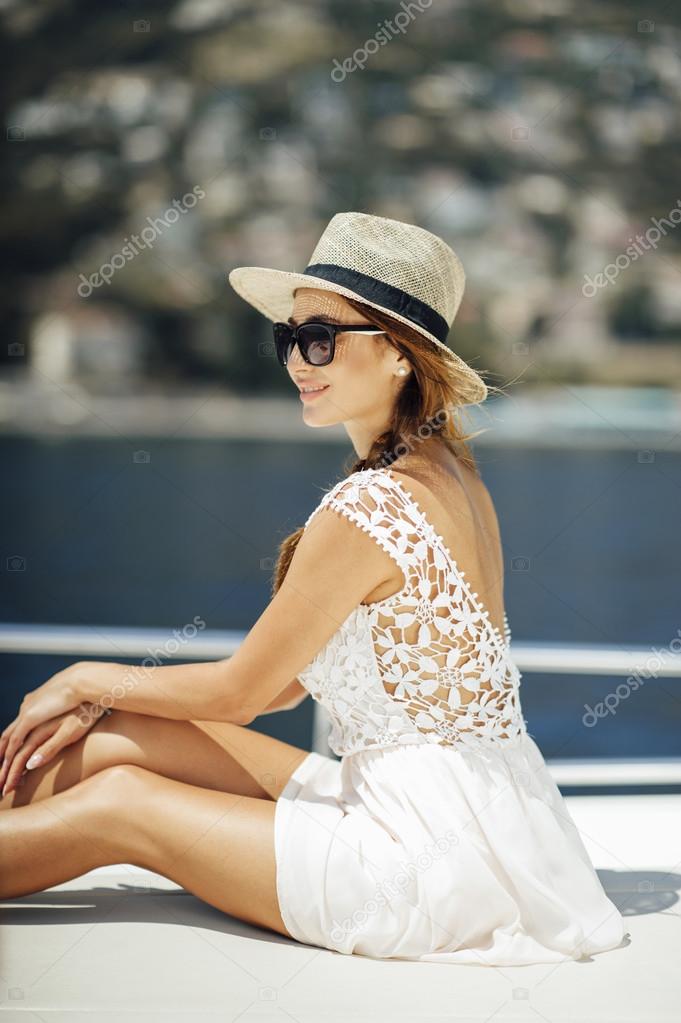 Attractive cute tanned girl on a yacht enjoy bright sun light on vacation