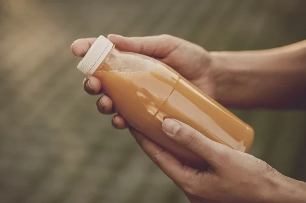 Vintage tarzı görüntü bir şişe kırmızı Detoks suyu ile açılış eller