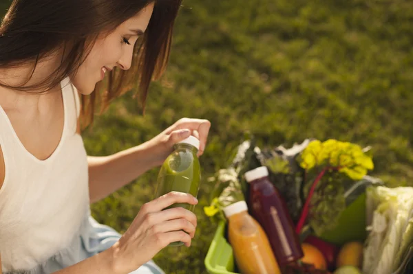 Vintage portrait of a beautiful smiling girl holding bottles of detox juice in her hands — Stock Photo, Image