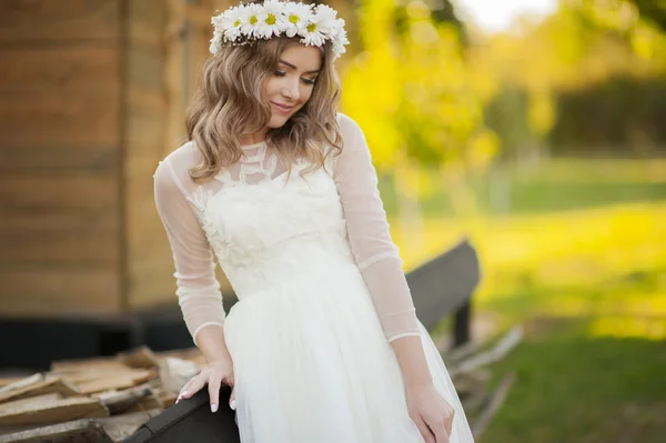 幸せな花嫁の笑顔のポーズし、彼女の白いドレスと花の冠を楽しんでいます — ストック写真