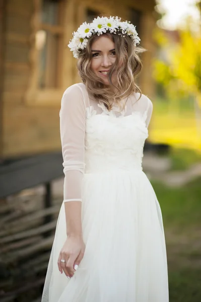 幸せな花嫁の笑顔のポーズし、彼女の白いドレスと花の冠を楽しんでいます — ストック写真