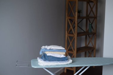 Ütü masasının üzerinde ütü bulunan ev kıyafetleri bakım alanı düzenleme ve düzenli ev işlerini göstermeye hazır.