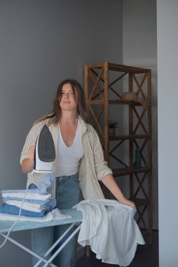 Evde kuru temizleme konsepti. Kadın dikkatli bir şekilde buğulanmış giysiler. Onlara temiz ve özenle bakılıyor.