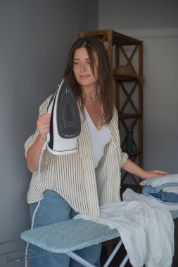 Kadın demiri tutmadan önce ev işlerini yapıyor. Temiz bir gardırop ve verimli bir gün sağlıyor.