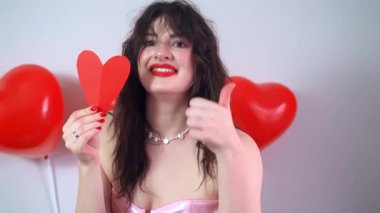 Bir kadın kağıt kalp şeklinde bir Sevgililer Günü 'nü kutlarken diğer eliyle baş parmağını kaldırır. Yüksek kalite 4k görüntü