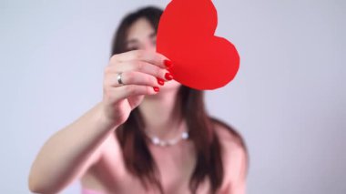 Pembe elbiseli mutlu bir kızın elinde Sevgililer Günü 'nü simgeleyen kırmızı bir Sevgililer Günü kartı var. Yüksek kalite 4k görüntü