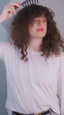 Sabah kendini sevme ile başlar: kıvırcık saçlı kadın buklelerini fırçalar ve kafa derisine rahatlatıcı bir masaj yapar. Yüksek kalite 4k görüntü