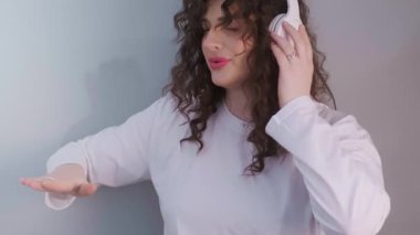 Mutlu ve enerjik kıvırcık saçlı, kablosuz kulaklık takan, yeni bir parça karıştıran ve sürecin tadını çıkaran bir DJ. Yüksek kalite 4k görüntü