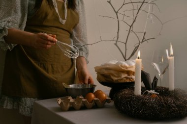 Sıcak Paskalya gelenekleri, kadın sıcak bir evde paskalya pastası için dikkatlice krema hazırlıyor..