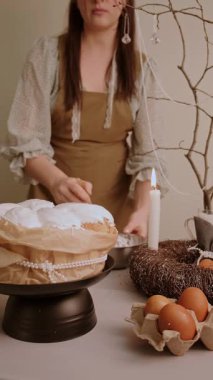 Sıcak önlüklü bir kadın Paskalya pastasını süslüyor. Evdeki şenlik masasını hazırlıyor. Yüksek kalite 4k görüntü