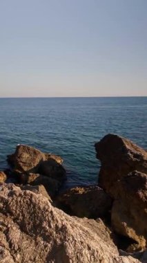 Sahili ve ufukta adalar olan orman dağlarını ortaya çıkaran kayalık kayalıkların arasından deniz manzarası. Yüksek kalite 4k görüntü