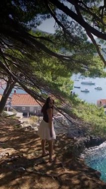 Uçan etek ve yaz kıyafetleri içinde Petrovac Riviera kıyı şeridi yeşil tepeler ve açık mavi Adriyatik Denizi manzaralı bir uçurum. Yüksek kalite 4k görüntü