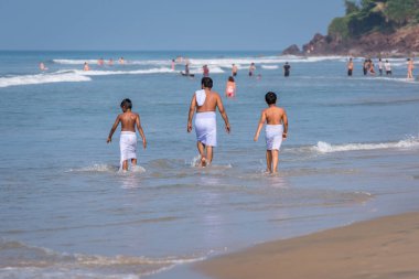 Geleneksel mayo giyen Hintli adam ve çocuklar Varkala, Kerala 'da denizin tadını çıkarıyorlar. Hindistan 'da aile tatili.