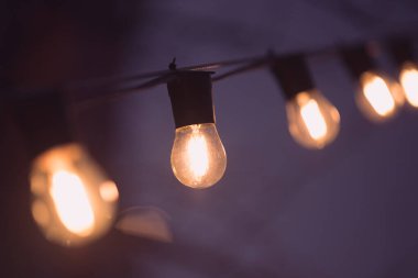 Karanlıktaki lamba çelenkleri. Mor gecede ılık turuncu ışık.