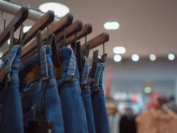 Moda niebieski jeans na drewniany wieszak w sklepie. Mody ubierać — Zdjęcie stockowe