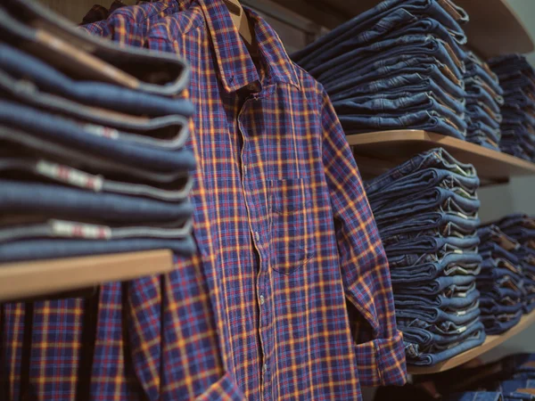 Shelves jeanswear. Retro Plaid shirt on the background of denim — Stock Photo, Image