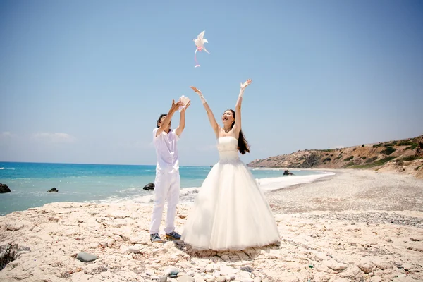 Mutlu gelin ve damat gülümseyen güneşli bir günde güvercinler beyaz serbest eller. Akdeniz. Kıbrıs