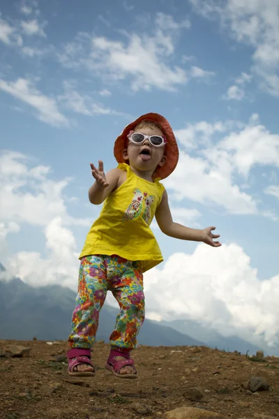 Criança pulando em um fundo de céu azul nas montanhas no verão — Fotografia de Stock