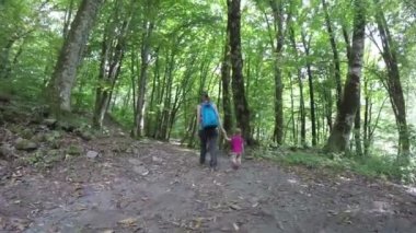 Anne kız elini pembe bir sırt çantası ile ormanda yürür. Sağlıklı bir yaşam tarzı. Aile açık havada ormanda yürümek. Tam Hd. 1920 x 1080