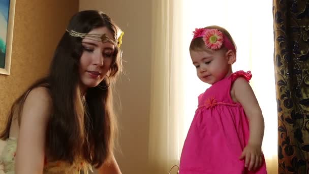 Maman met un rebord de fille sur les cheveux. petit enfant jouant avec sa mère dans la chambre sur un lit — Video