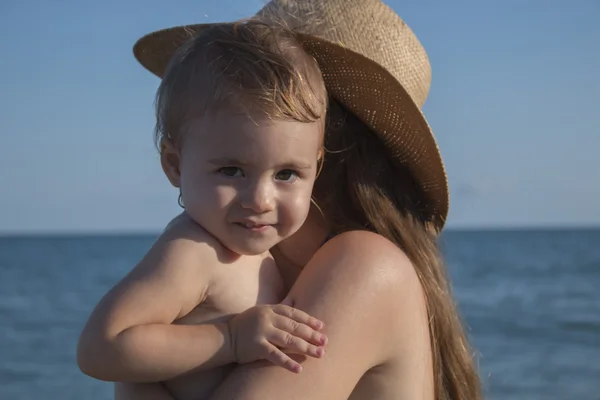 Ao ar livre clouse-up retrato menina pequena abraçando sua mamãe na praia. Verão dia ensolarado . Imagem De Stock