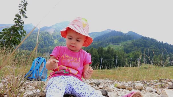 Un niño pequeño sentado en las montañas de un caluroso día de verano. Full HD. 1920x1080 — Vídeo de stock