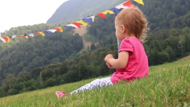 Pequeño bebé sentado en la hierba verde en las montañas en un día caluroso de verano. Full HD. 1920x1080 — Vídeos de Stock