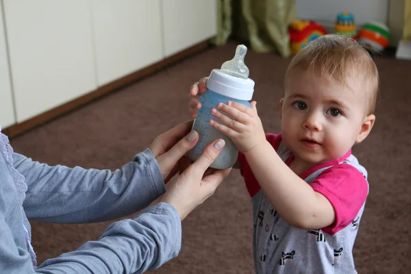 Mama daje butelkę mleka do ich młode dziecko. — Zdjęcie stockowe