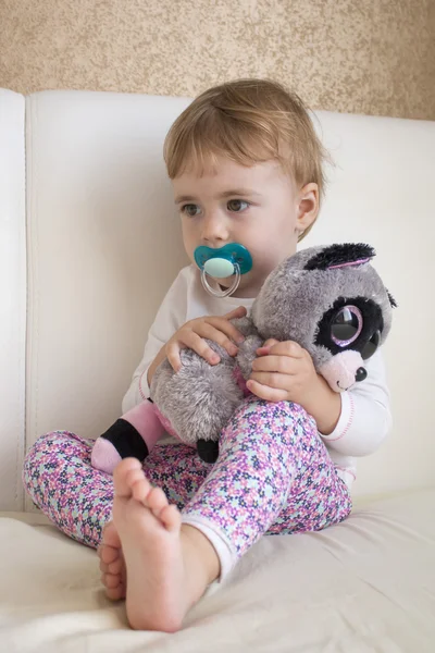 Retrato clouse-up niño pequeño sentado en la cama en la habitación abrazando un lémur juguete relleno — Foto de Stock