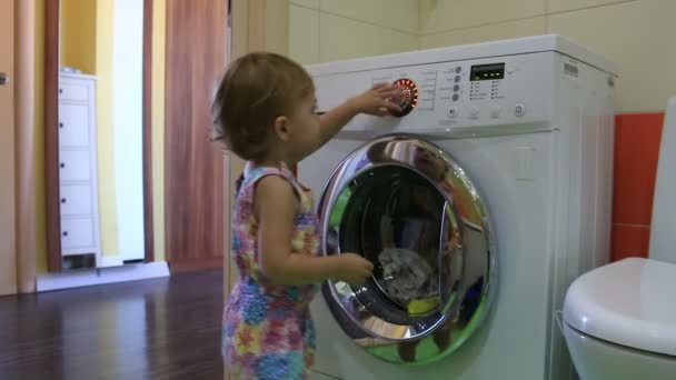 Little kid starts washing machine in the bathroom. HD. — Stock Video