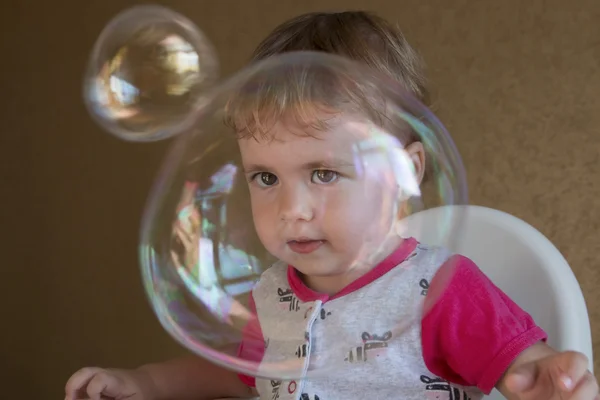 Clouse-up portrait two-year girl inflates a large circular bubble — Stock Photo, Image