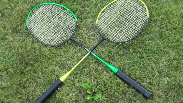 Raquetas de bádminton sobre hierba verde de verano. mano masculina y femenina toma la raqueta — Vídeo de stock