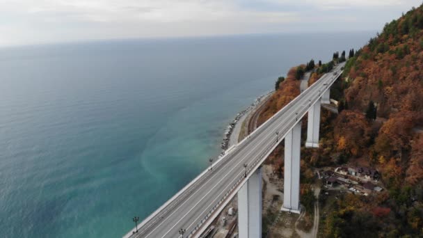 Letecký pohled na dálniční viadukt na betonových pilířích v horách. Let dronem nad autobahnem na pozadí moře. Automobilový provoz na mostě. Leť nad vozidly. 4k — Stock video