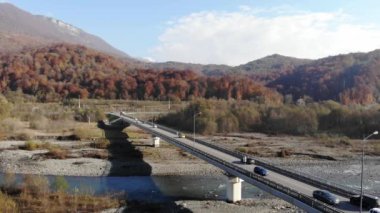 Otoyol Viyadük 'ünün havadan görüntüsü. İnsansız hava aracı otobanın üzerinden dağların arka planına doğru uçuyor. Köprü yolunda trafik var. Araçların üzerinden uç. 4k
