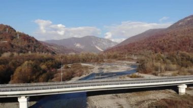 Otoyol Viyadük 'ünün havadan görüntüsü. İnsansız hava aracı otobanın üzerinden dağların arka planına doğru uçuyor. Köprü yolunda trafik var. Araçların üzerinden uç. 4k