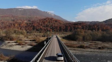 Nehrin üzerindeki köprüde uçan bir aracın insansız hava aracından ateş edişinin hava görüntüsü. Sinematik 4K hava görüntüleri.