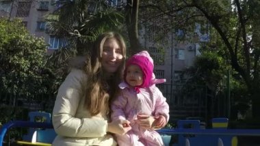 Anne ve kızı sonbahar güneşli günü parkta bir salıncak üzerinde. ağır çekim. Full Hd