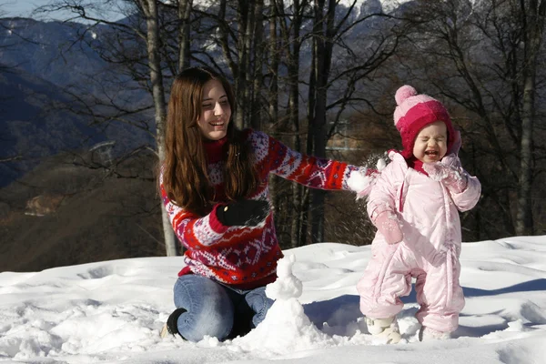 Anne ve kızı karda oynuyorlar.