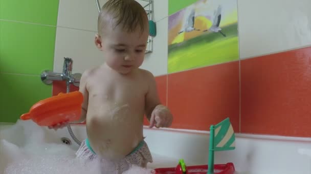 Niño feliz niña con un juguete se baña en un baño — Vídeo de stock