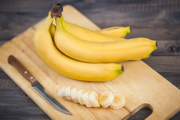 ahşap tahta üzerinde bir bıçakla dilimlenmiş muz