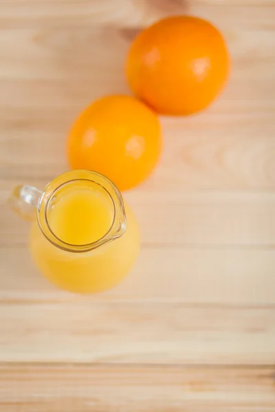 Χυμό πορτοκαλιού σε σαφή βάζο σε φόντο ξύλινη — Φωτογραφία Αρχείου