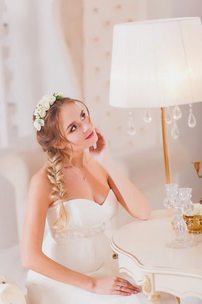 Красива наречена блондинка у весільній сукні, що носить перед дзеркалом — стокове фото